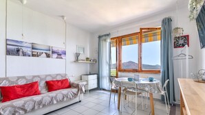 Un salon comprenant un canapé, une table à manger, des chaises, une fenêtre donnant sur les montagnes et un luminaire au plafond.