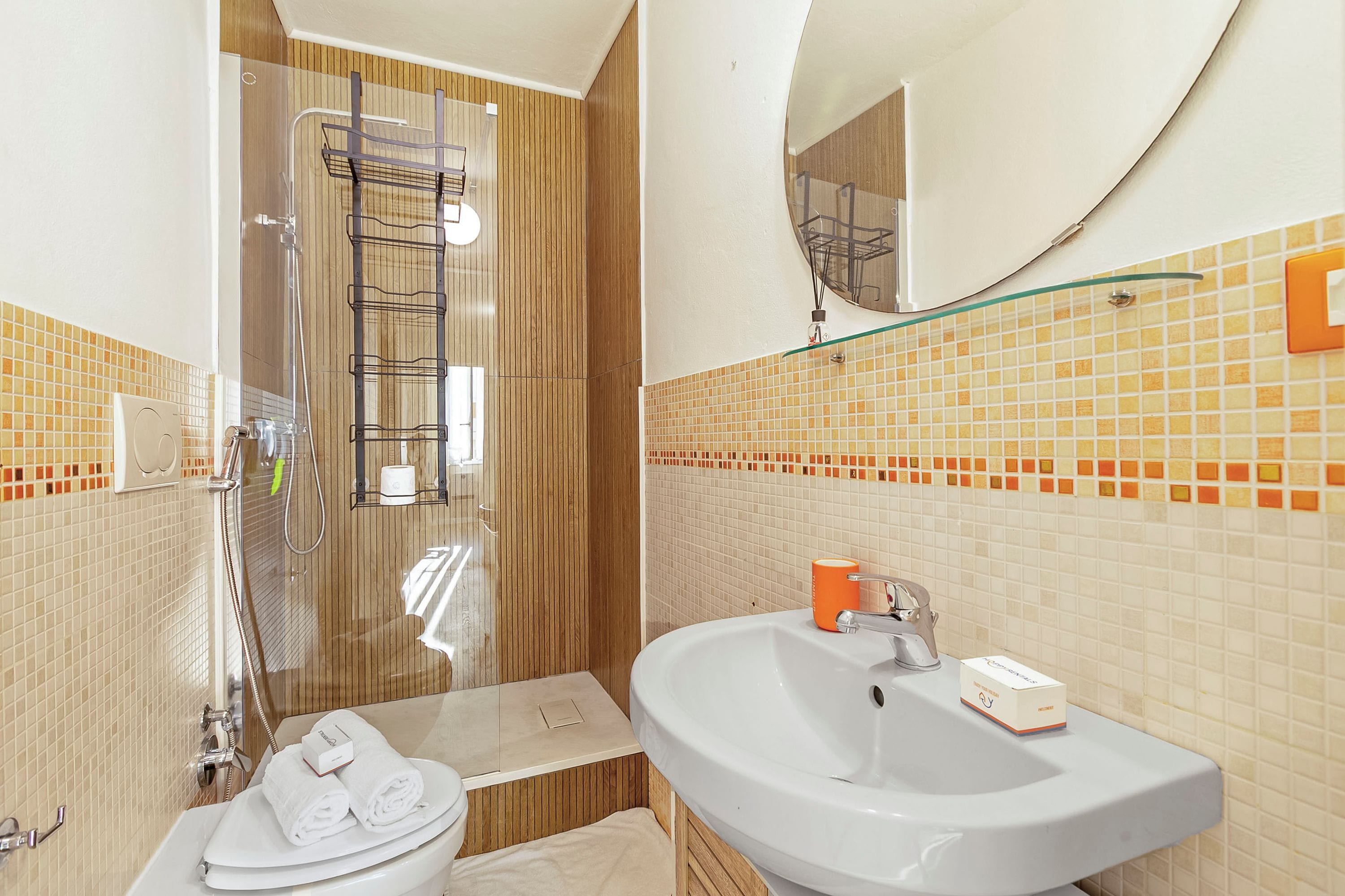 Un baño con ducha, inodoro, lavamanos y espejo.