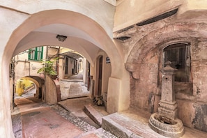 An arched corridor with a fountain, a staircase, and a view of a street with buildings. - EA Blue Marin Apartment With A/C (Sanremo)