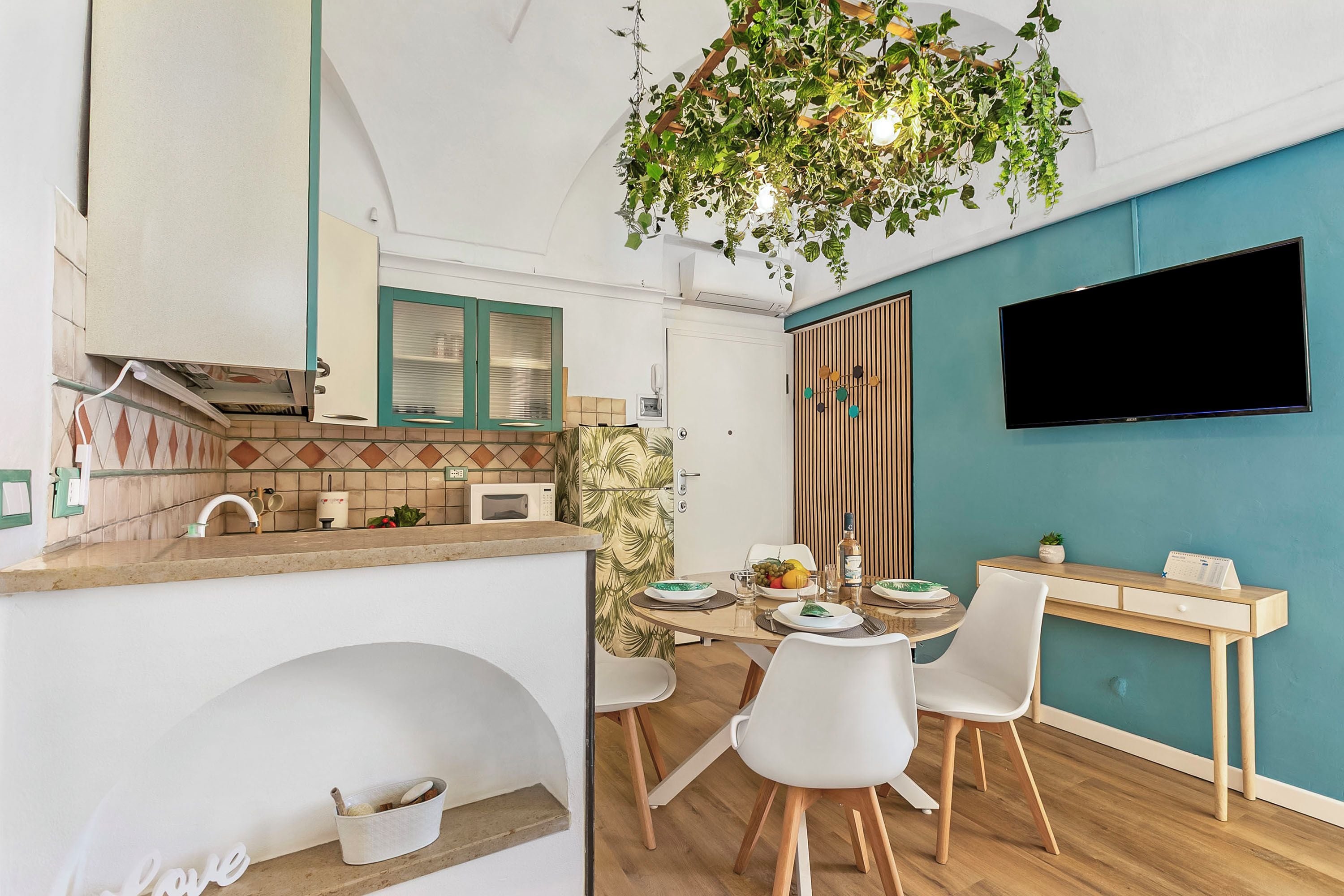 Una cocina moderna con microondas, pileta y comedor con mesa y sillas.