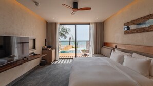 A hotel room with a bed, TV, and a view of the pool and ocean. - Riva Hua Hin (Hua Hin)