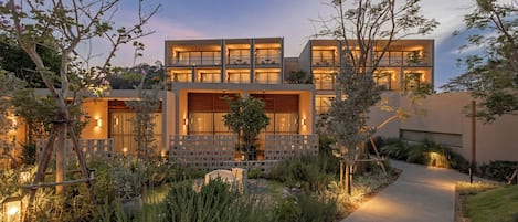 A modern two-story house with a well-lit garden and a paved pathway.