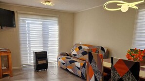Un salon comprenant un canapé, une table à manger avec des chaises, un téléviseur et une cheminée.