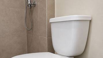 Sanitário com função bidê, lixeira preta e piso revestido de azulejos bege.