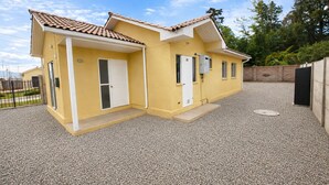 Un immeuble résidentiel de deux étages, avec une façade jaune, un toit en tuiles et une allée gravillonnée.