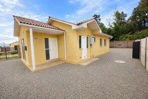 Un immeuble résidentiel de deux étages, avec une façade jaune, un toit en tuiles et une allée gravillonnée.