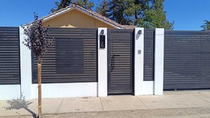 Il s’agit d’une propriété privée, dotée d’une conception moderne, avec un portail en métal et un mur blanc.