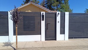 En lukket ejendom med moderne design, med en metalport og en hvid mur.