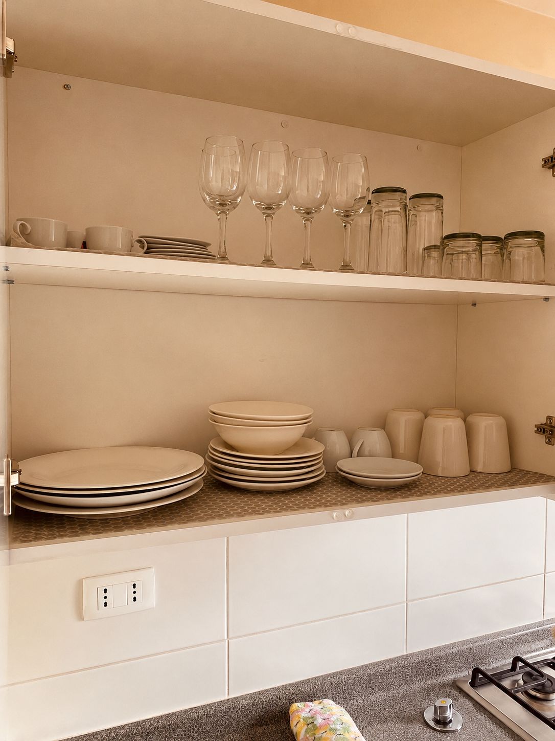 A kitchen with white cabinets, a countertop with glassware, plates, and jars.