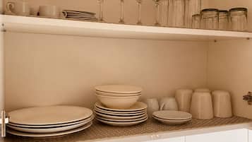 A kitchen with white cabinets, a countertop with glassware, plates, and jars.