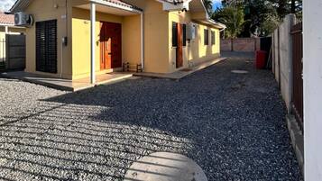 Um edifício residencial com telhado de cerâmica, entrada por um caminho de cascalho e tampa de metal para bueiro.