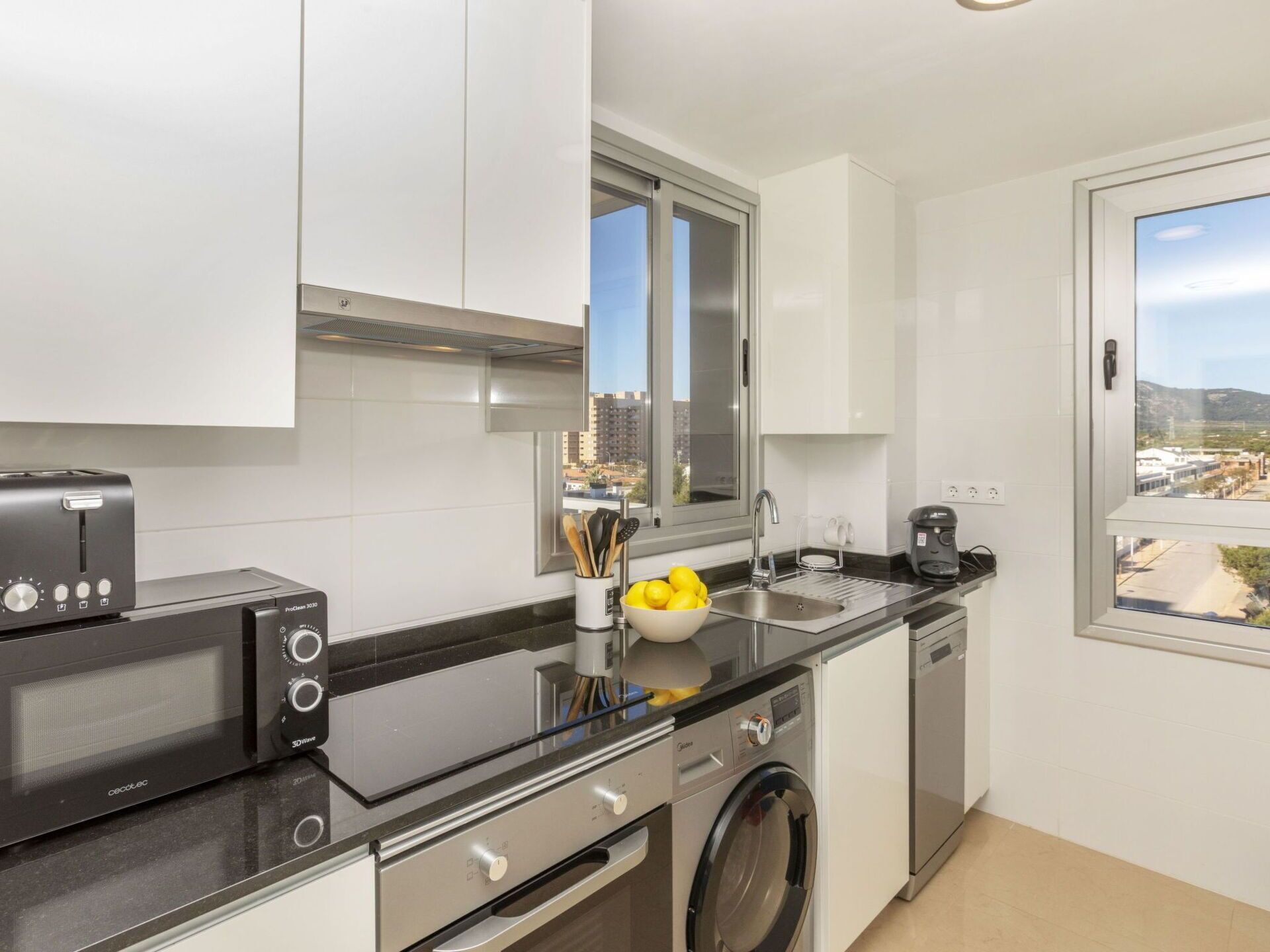 A modern kitchen with a microwave, toaster, sink, and washing machine.