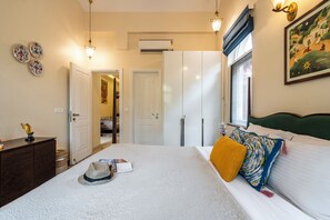 A bedroom with a bed, a dresser, a window with curtains, and a painting on the wall. - Staymaster Una 4BR Villa (Assagao)