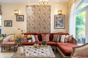 A living room with a sofa, a coffee table, and a patterned wall. - Staymaster Una 4BR Villa (Assagao)