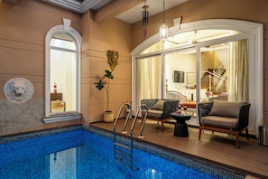 A pool area with a wooden deck, lounge chairs, and a glass-enclosed room with a view. - Staymaster Una 4BR Villa (Assagao)