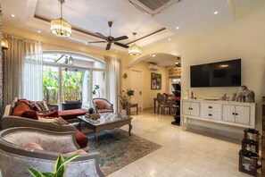 A spacious living area with a sofa, armchairs, a dining table, and a television. - Staymaster Una 4BR Villa (Assagao)