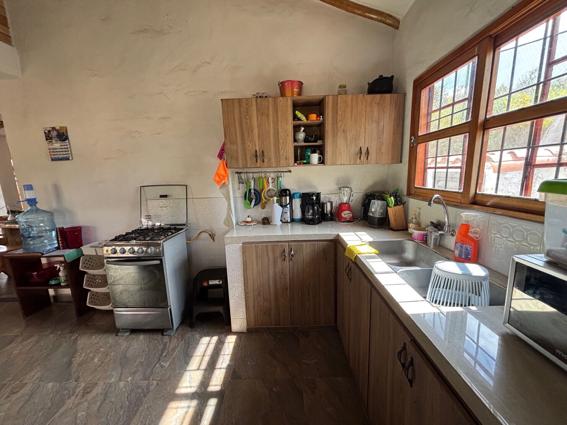 Une cuisine avec des meubles de rangement en bois, une cuisinière à gaz, un évier et divers ustensiles de cuisine.