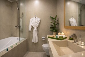 Ein modernes Badezimmer mit einer gläsernen Duschkabine, einer weißen Badewanne, einer Toilette und einem Waschtisch mit Spiegel.