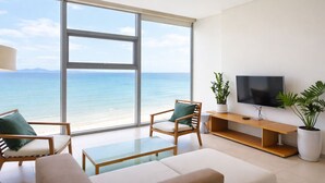 Un soggiorno moderno con una grande finestra vista spiaggia, una televisione a schermo piatto e un design minimalista.