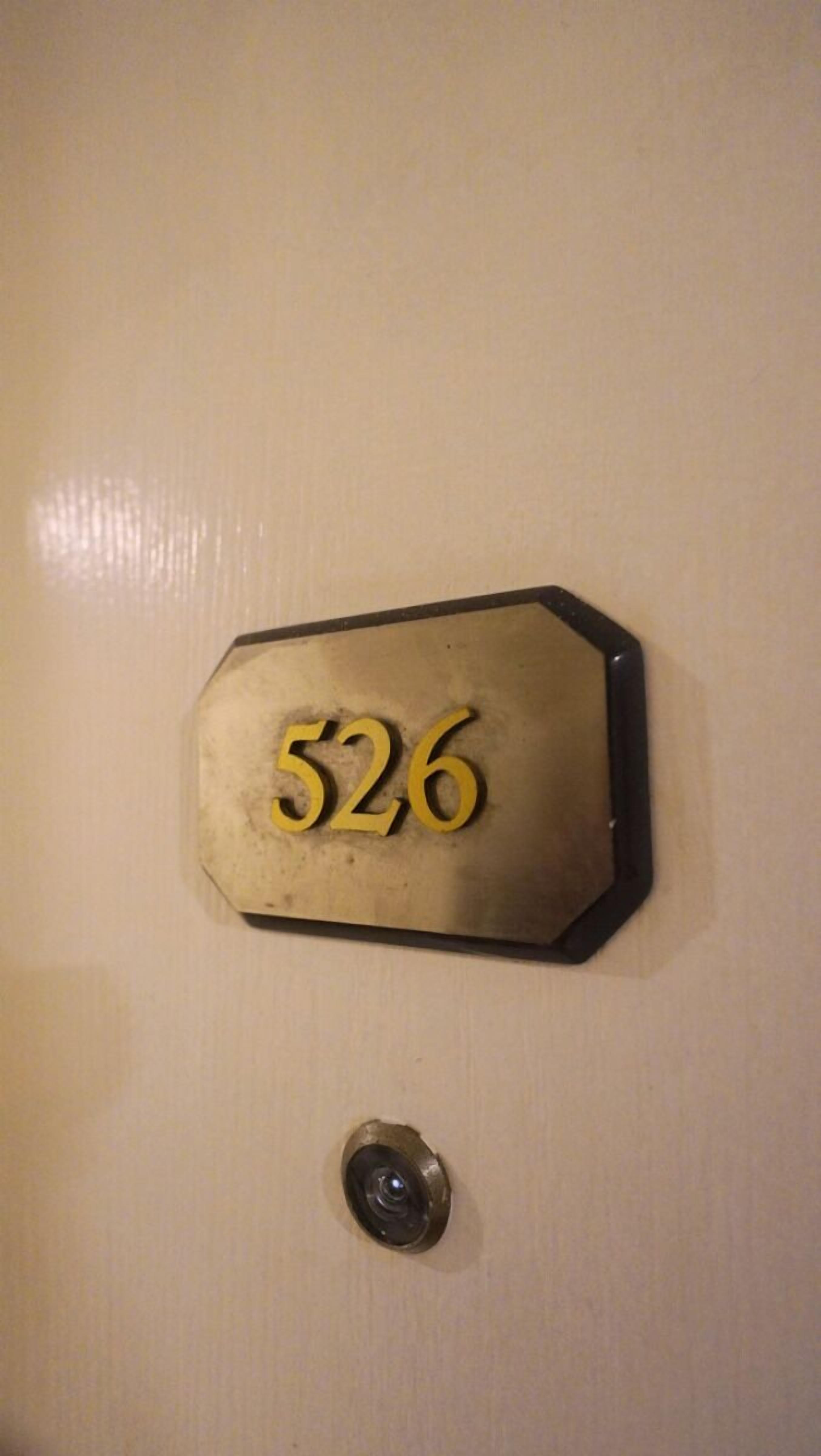 En dør med et nummer på skiltet, der viser '526', og en ringeklokke nedenunder.