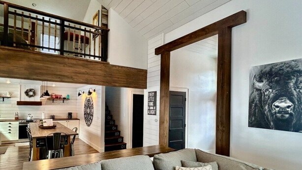 Una sala de estar con sofá, una escalera, cocina y comedor.