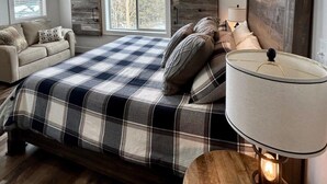Un dormitorio con cama, sofá, lámpara y vistas al exterior.