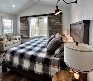 A bedroom with a bed, a sofa, a lamp, and a view of the outdoors. - TT CastIron Open layout, EV, close2Yellowstone, hotTub, AC (Island Park)