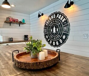 A kitchen with a wooden island, a wall-mounted sign, and a shelf with kitchen items. - TT CastIron Open layout, EV, close2Yellowstone, hotTub, AC (Island Park)