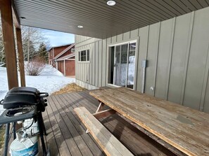 A covered outdoor area with a wooden table and grill, a propane tank, and a metal structure. - TTM Open layout, EV, close2Yellowstone, hotTub, AC (Island Park)
