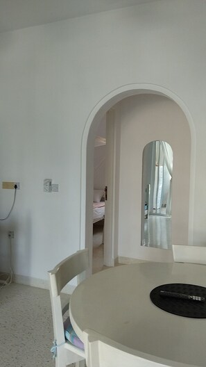 A room with a round table, a chair, a bed in the background, and a mirror on the wall. - Casa Di Philo 1
Four Steps To The Beach, (Watamu)