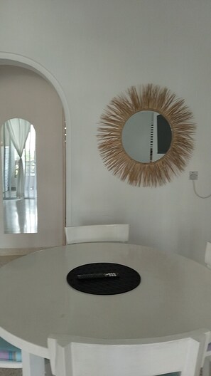 A round table with a remote control on it, a wall-mounted mirror with a fringe design, and a doorway leading to another room. - Casa Di Philo 1
Four Steps To The Beach, (Watamu)