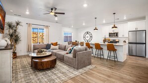 A modern living room with a sofa, coffee table, and a dining area with chairs. - Skyline 1742, Private Spa, Fire Pit, Community Amenities! (Washington)