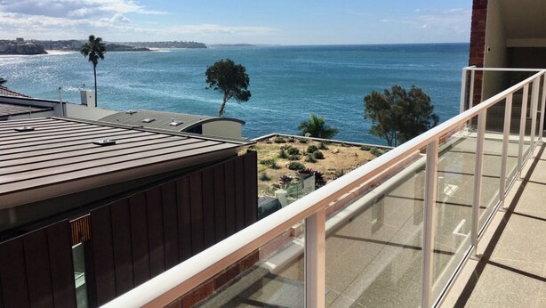 Ein Balkon mit Blick auf den Ozean, einen Strand und eine entfernte Küstenlinie.
