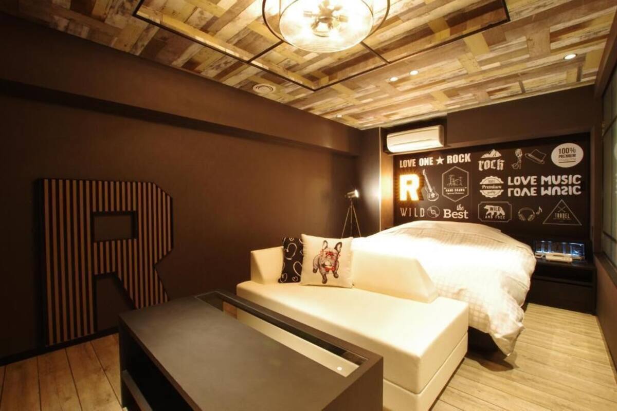 Une chambre à coucher moderne avec un plafond en bois, un grand lit, une table de chevet et un mur orné de divers textes et icônes.
