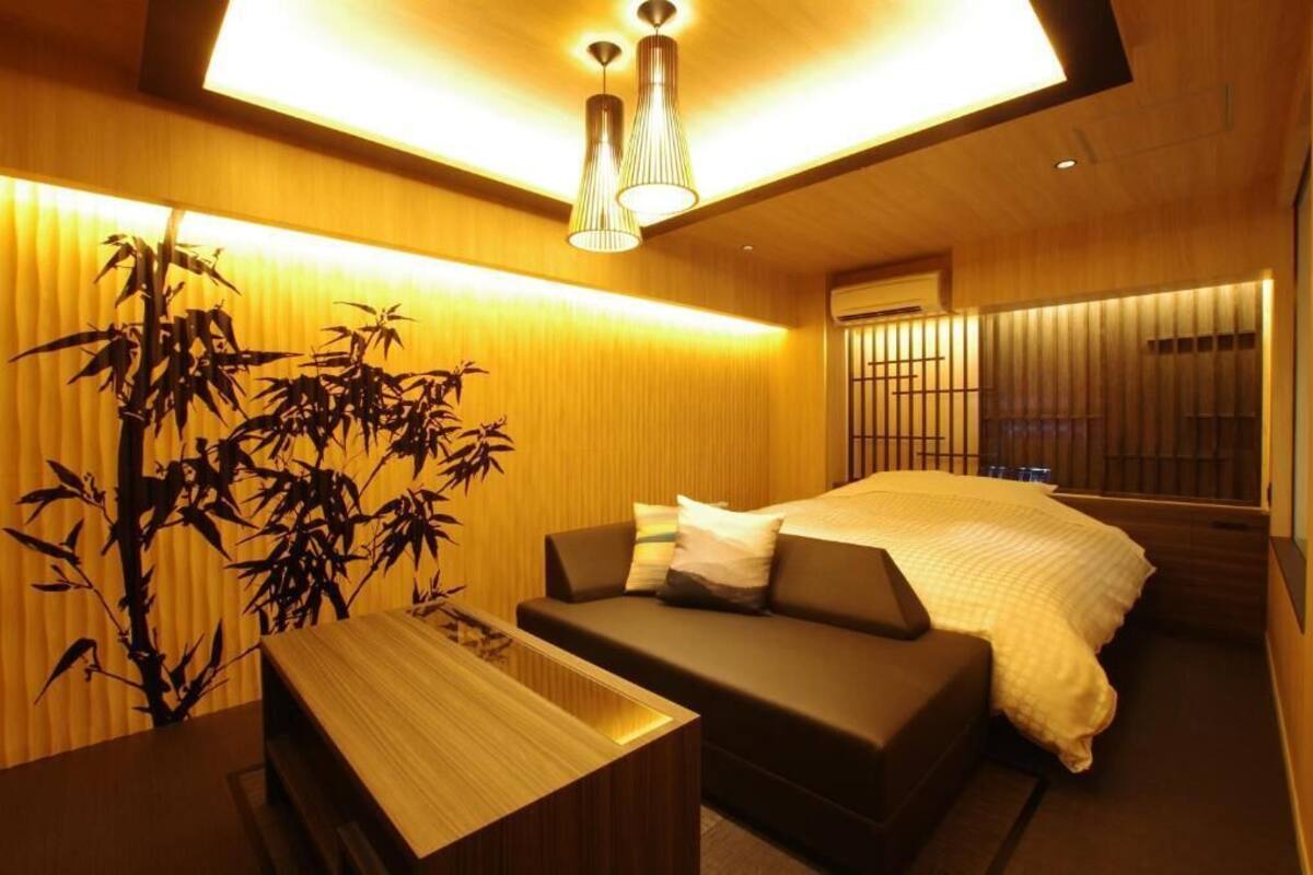 Une chambre d’hôtel moderne, équipée d’un lit, d’un canapé, d’une table en bois et d’une grande plante en bambou.