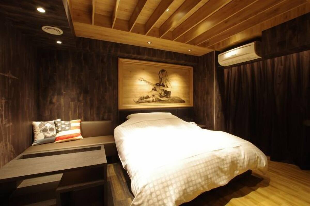 Une chambre à coucher avec un lit, une table de chevet, un climatiseur fixé au mur et un tableau.