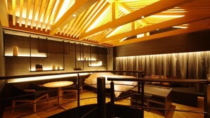 A modern hotel room with a wooden ceiling, a bed, a desk, and a seating area.