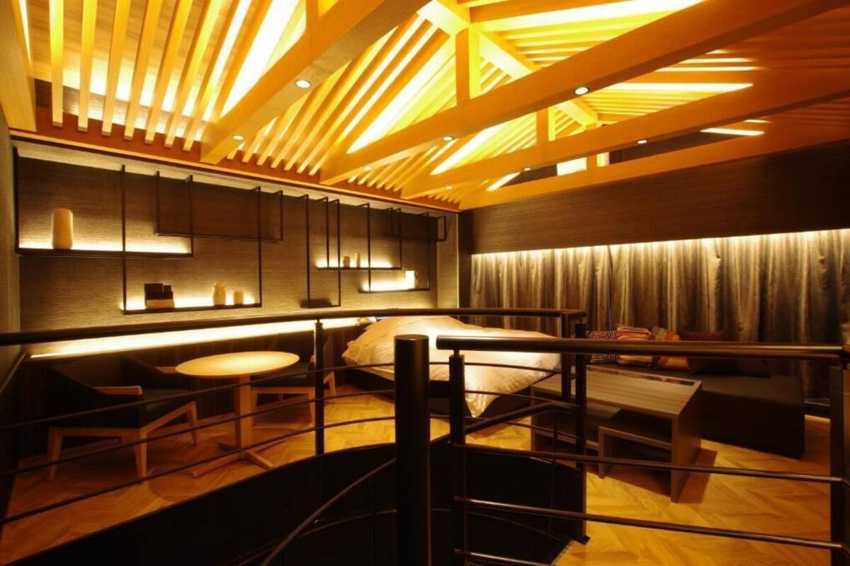 Une chambre d’hôtel moderne avec un plafond en bois, un lit, un bureau et un coin salon.