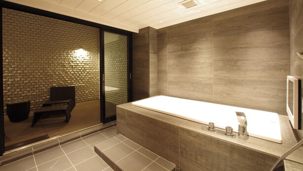 A modern bathroom with a large bathtub, a glass shower enclosure, and a seating area with a chair and a small table.