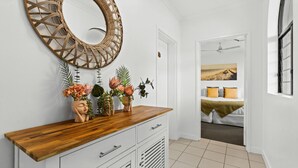 Ein Zimmer mit einer Holztische, einem großen Spiegel und drei Blumentöpfen mit Blumen.