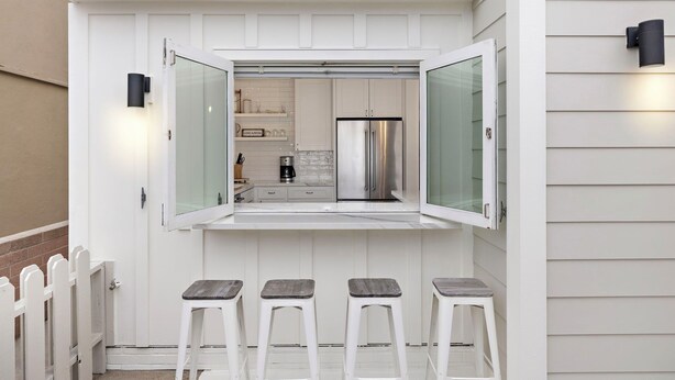 Une cuisine moderne dotée d’une paroi en verre, d’appareils électroménagers en acier inoxydable et d’une façade blanche.