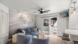 Un salon moderne avec un canapé bleu, une table basse en bois et un ventilateur de plafond.