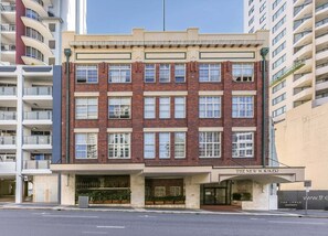 Um edifício de vários andares com arquitetura clássica, destacando uma entrada imponente com a placa 'THE NEW YORKER'.