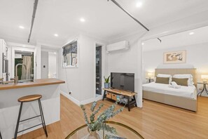 Ein modernes Schlafzimmer mit Bett, Nachttischen und Fernseher.