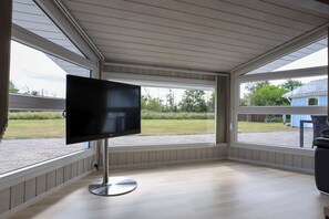 Ein Zimmer mit einem großen Fenster, einem Flachbildfernseher und einem runden Tisch.