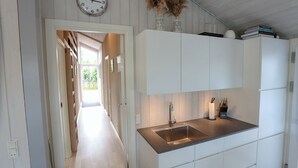 Une cuisine avec des armoires blanches, un évier en acier inoxydable et une horloge au mur.