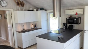 Une cuisine moderne avec des meubles blancs, une hotte de cuisinière en acier inoxydable et un four à micro-ondes encastré.