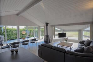 Un grand espace de vie comprenant un canapé, une table à manger avec des chaises, un téléviseur et une cheminée.