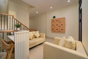 A modern living room with a staircase, a dining area, and a storage unit with numbered compartments. - Dalat Blanc Residence (Cam Ly - Da Lat)