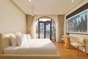 A hotel room with a large bed, a desk, and a TV screen displaying a movie scene. - Dalat Blanc Residence (Cam Ly - Da Lat)